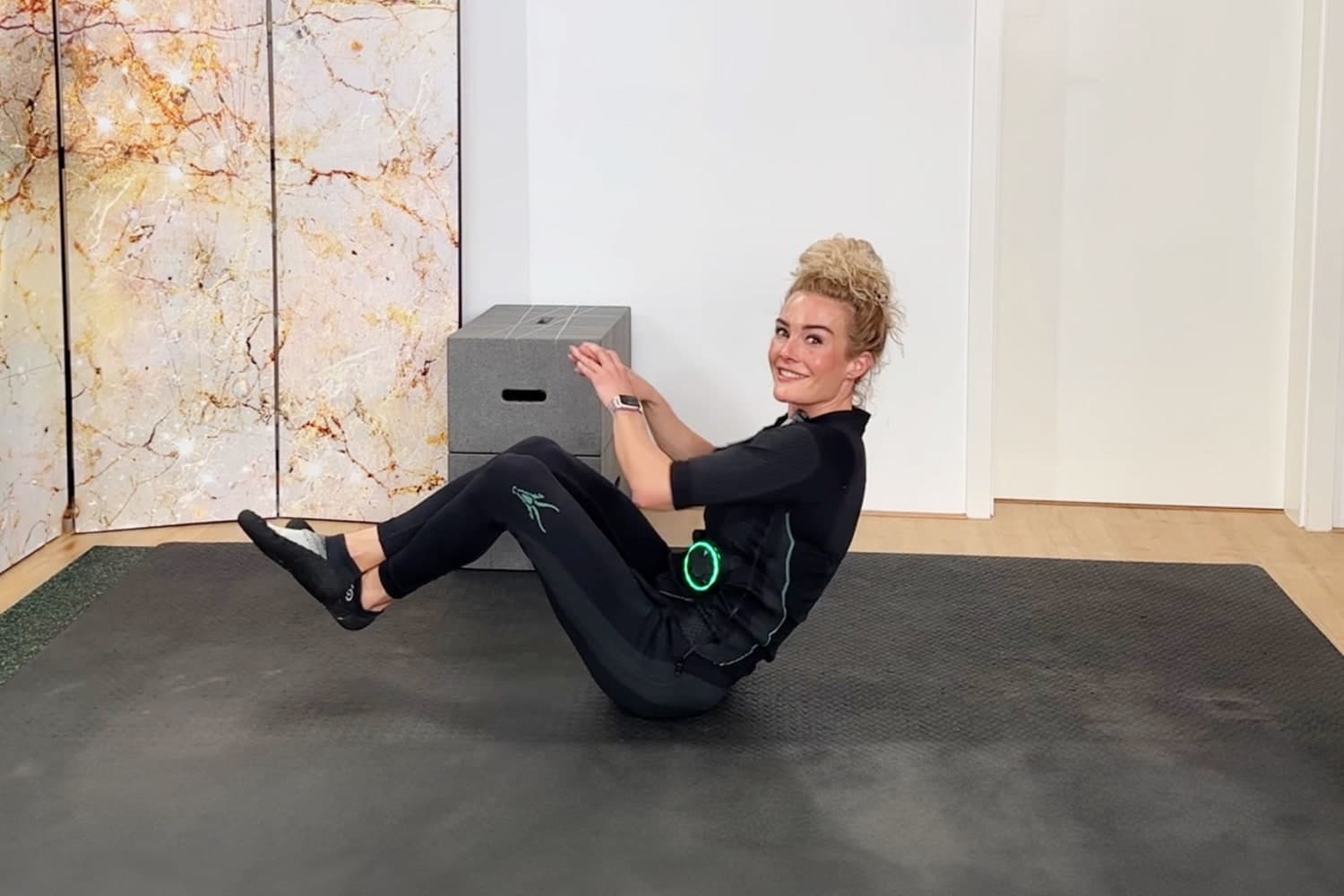 Jessica Wilens beim Workout. Sie führt einen Russian Twist aus und trägt den EMS Anzug von Antelope.